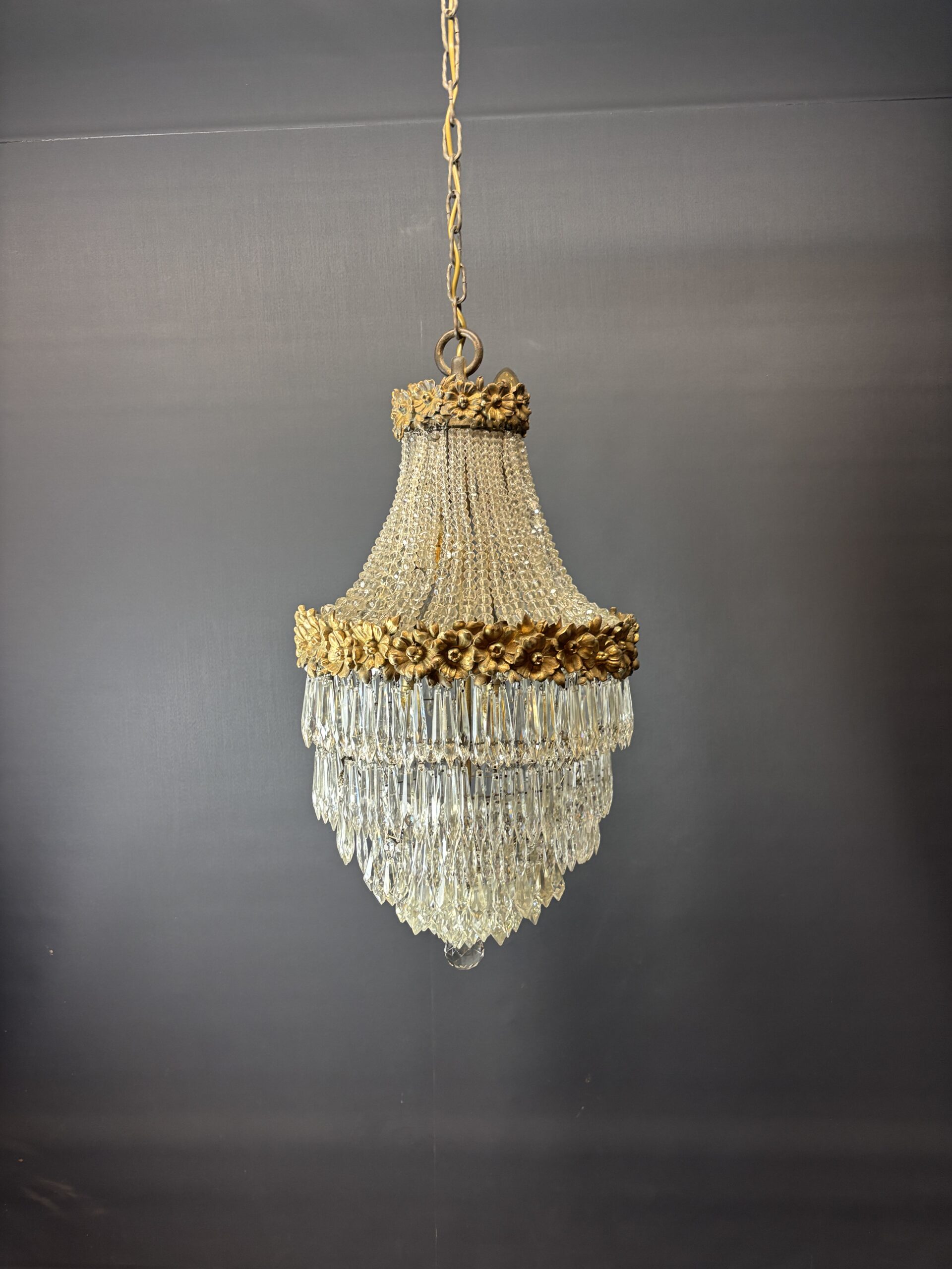 Glamorous chandelier dripping with crystals and crowned with gilded flowers.